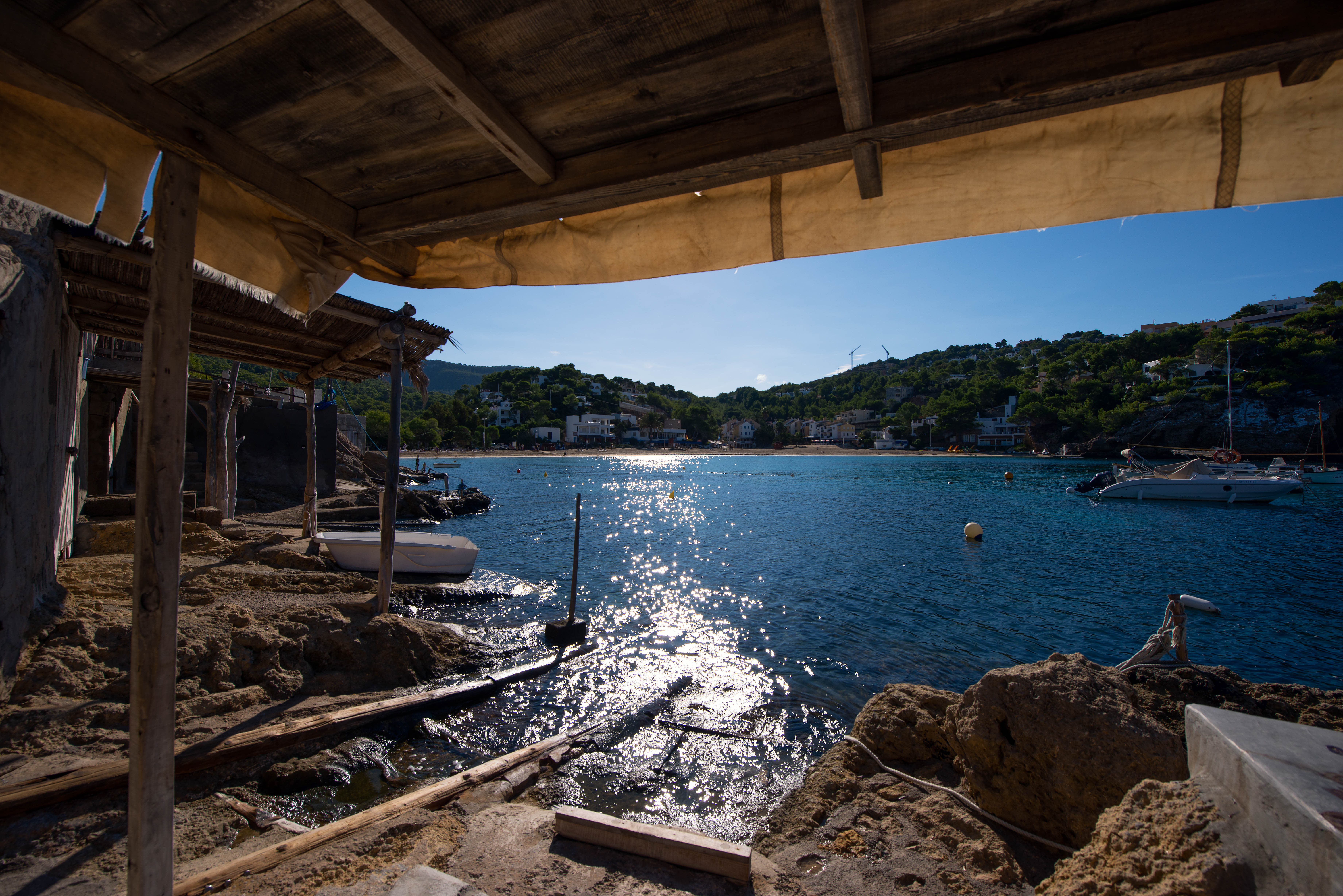 Cala Vadella bay seen from under the traditional fishing boat sheds