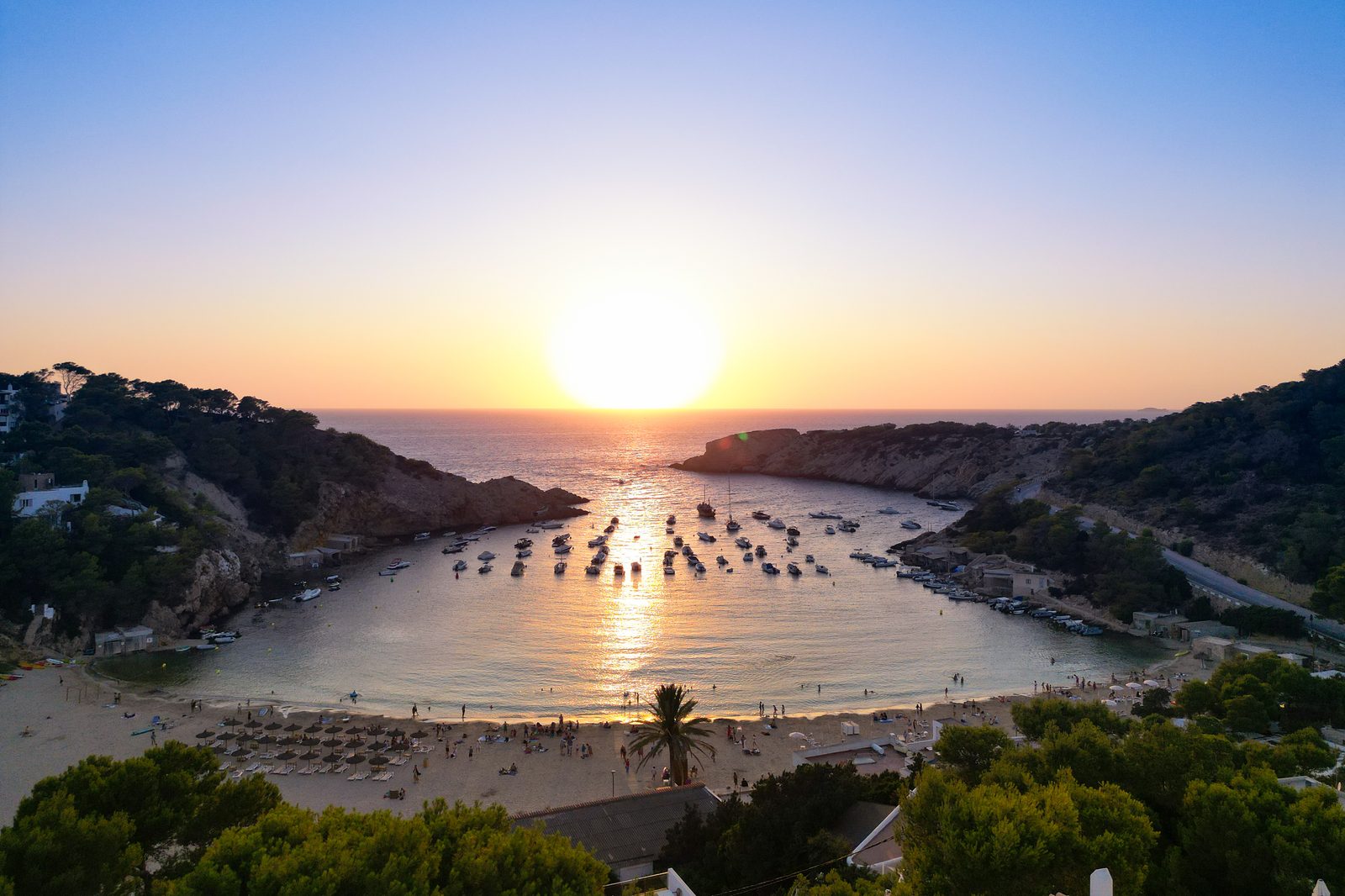 Cala Vadella bay at sunset — sailboats anchored in turquoise water