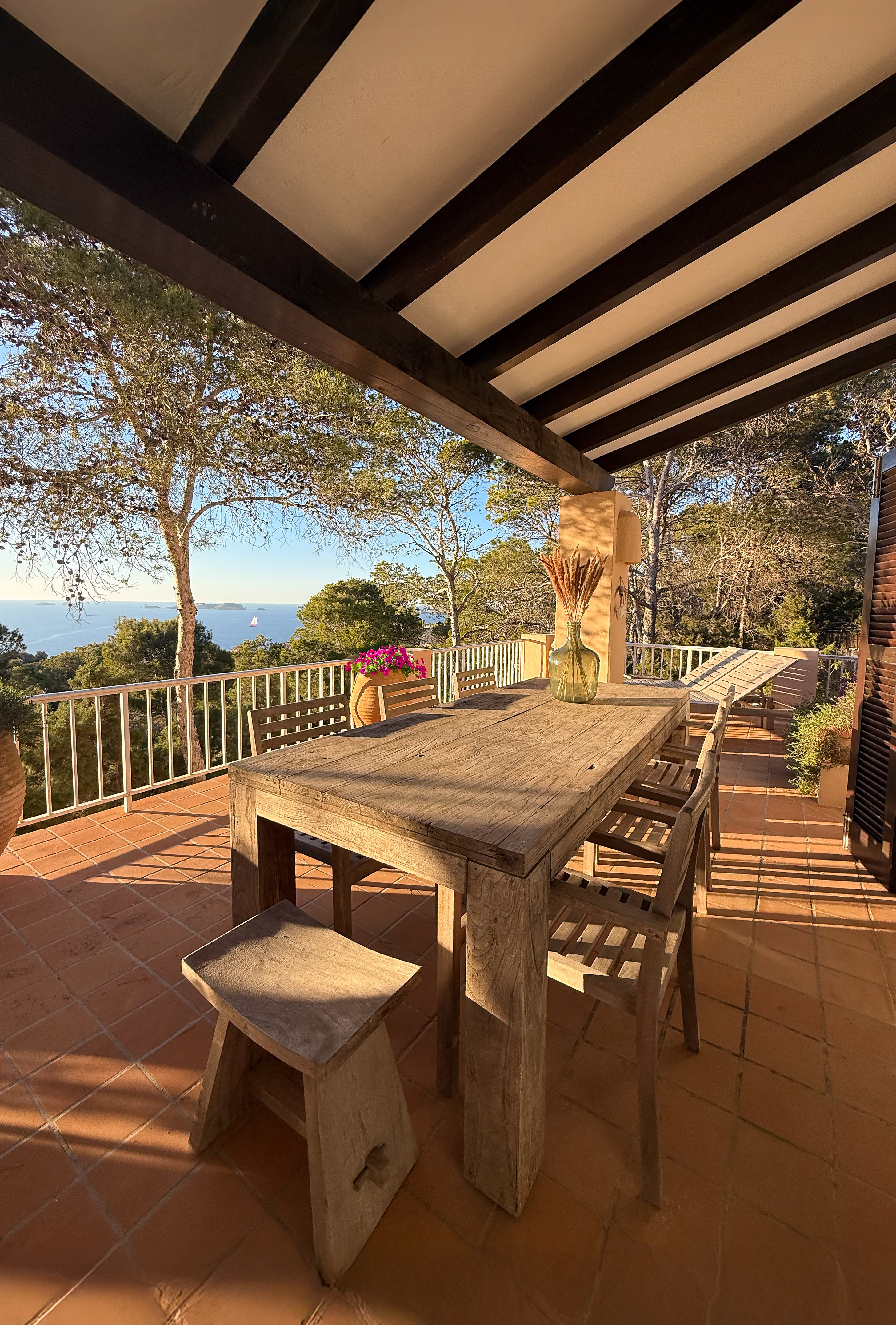 Covered terrace dining table with wooden furniture and sea view at Can Beteigeuze